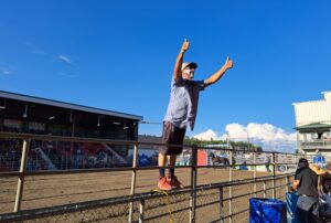 Un homme debout sur une clôture anime la foule devant lui lors d'une compétition de rodéo