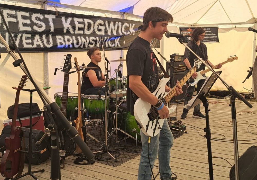 Trois en membre d'une groupe de musique rock en action durant un test de son, sur une scène