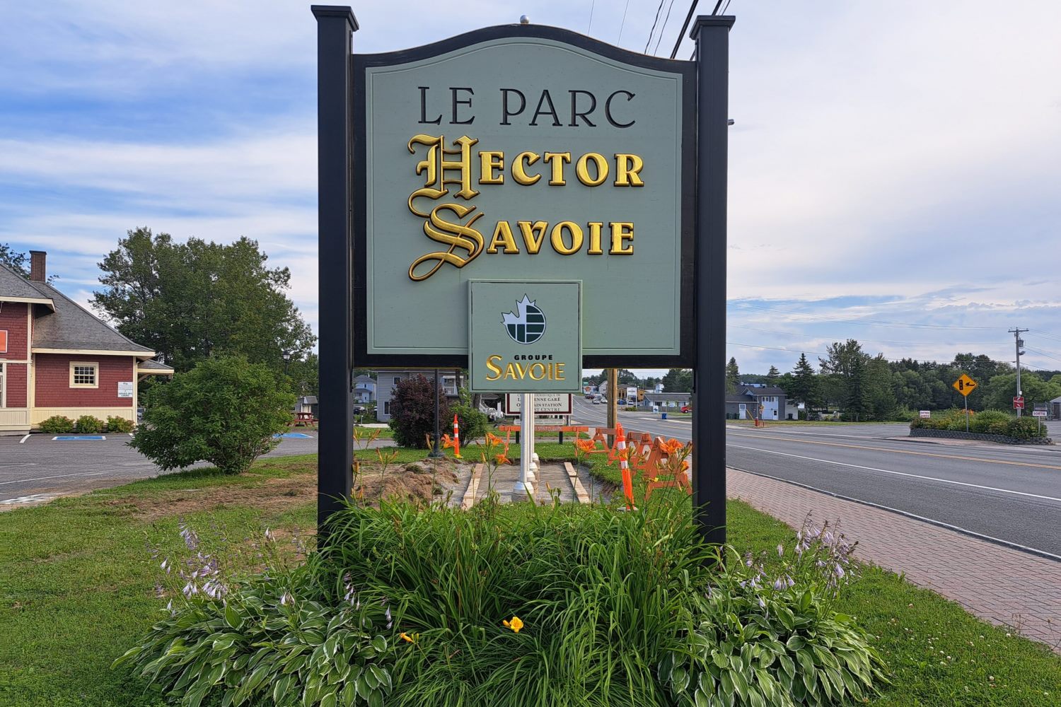 Panneau indiquant le parc Hector Savoie, décoré de plantes en bas.