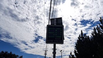 Panneau d'afficheur de vitesse en dessous de fils électriques et d'un ciel partiellement couvert.