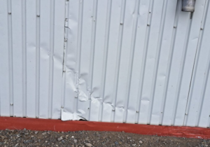 Mur de tôle blanc endommagé par des actes de vandalisme