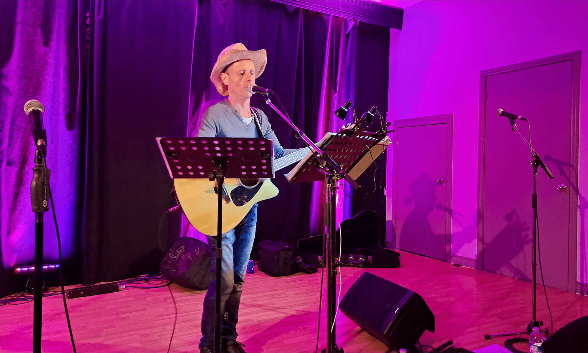 Un chanteur tenant sa guitare et portant un chapeau de cowboy, en performance durant un concert.