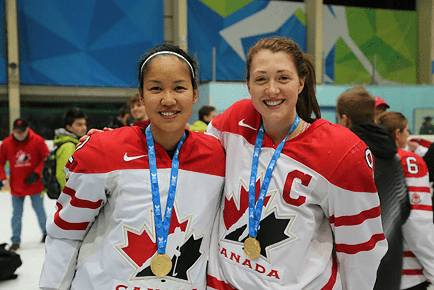 Deux femmes portant l'uniforme de l'équipe du Canada au hockey, affichant fièrement leur médaille