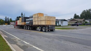 Camion poids lourd avec des planches de bois chargées circulant dans un rue