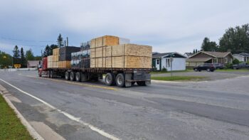 Camion poids lourd avec des planches de bois chargées circulant dans un rue