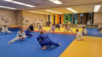 Des judokas font des étirements lors d'un entrainement de judo dans un dojo.