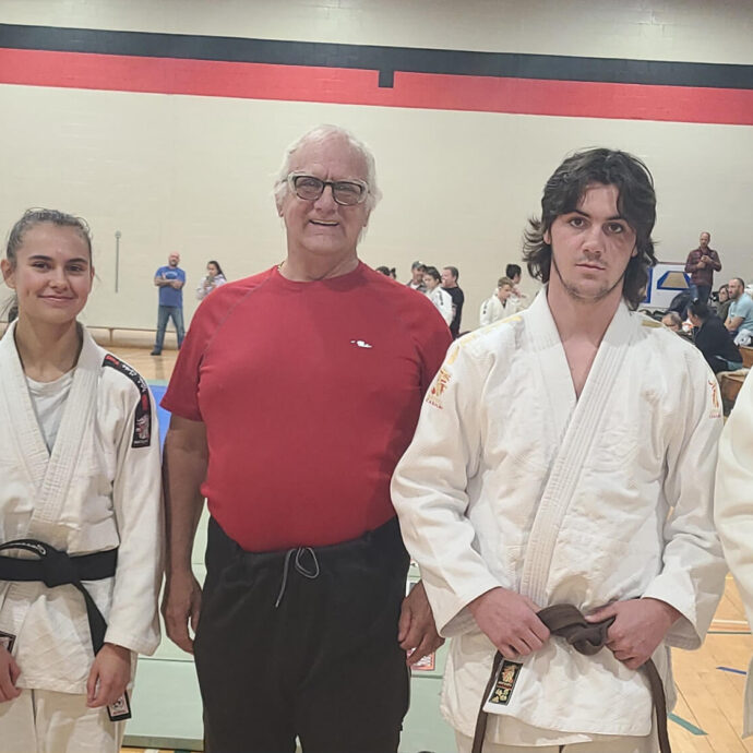 4 judokas avec au milieu un homme au gilet rouge, lors d'une compétition de Judo à l'intérieur d'un gymnase.