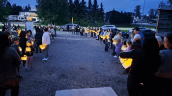 Des personnes sont en ligne en tenant chacune une lanterne lumineuse dans leurs mains. en attente avant le début d'une marche de groupe alors que la nuit tombe.