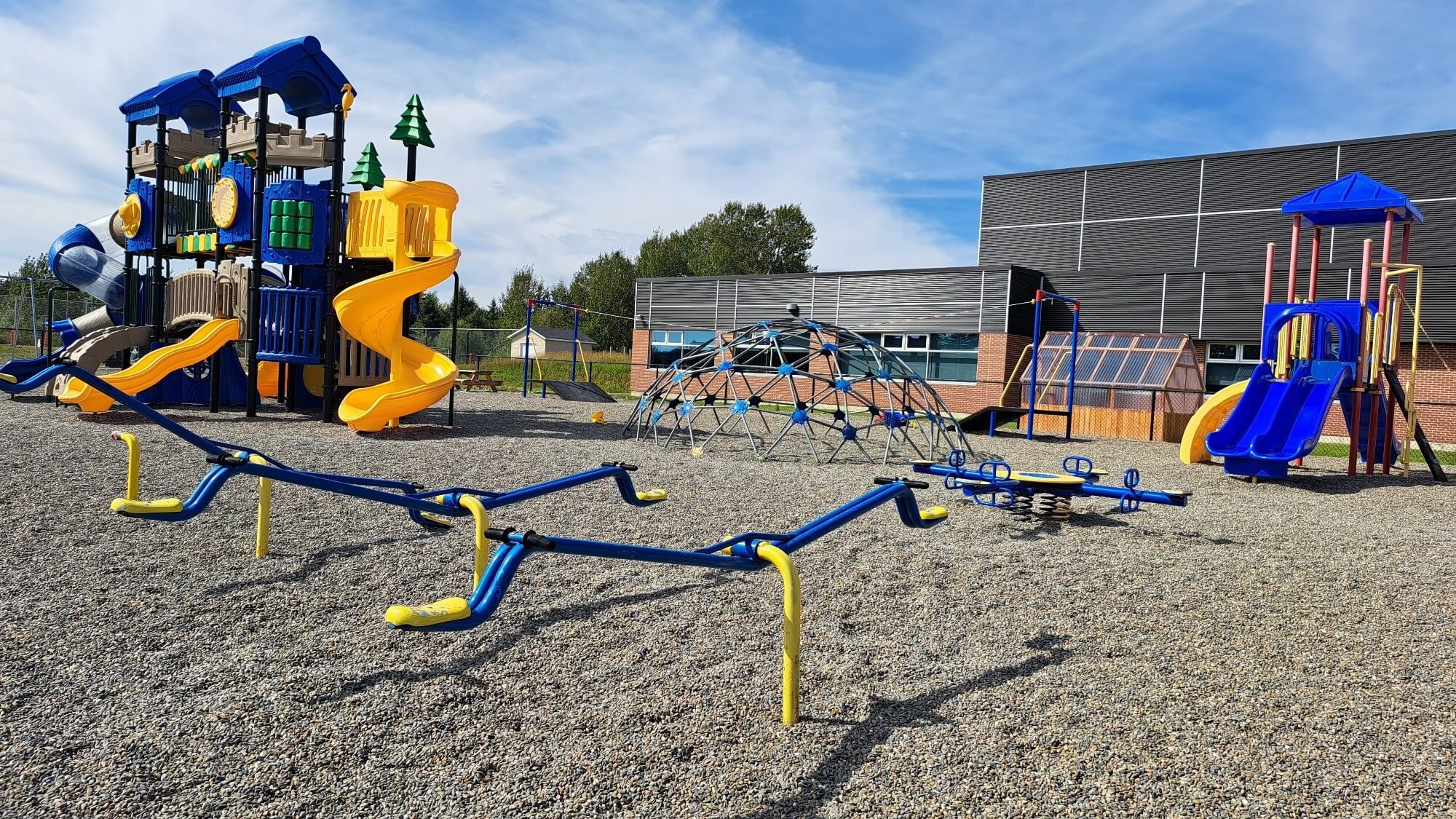 Cours de récréation avec plusieurs modules de jeux avec une surface de sables.