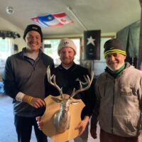 Trois hommes portant une tuque tiennent leur trophée après avoir remporté un tournoi de golf.