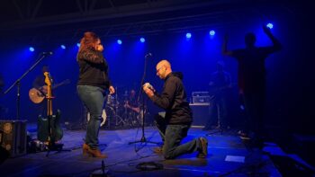 Un homme demande sa conjointe en mariage sur une scène pendant un spectacle.