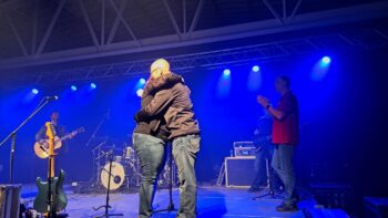 Un couple se donne un câlin sur une scène lors d'un concert.