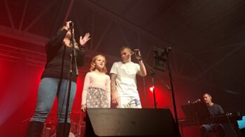 Un femme, une jeune fille et Olivier Bergeron sont sur scène pour chanter une chanson.