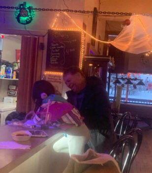 Un homme souriant assis à côté d'une enfant, au comptoir d'un bar.