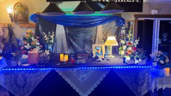 Table décoré en bleu, avec photos et fleurs, pour rendre hommage à un défunt.
