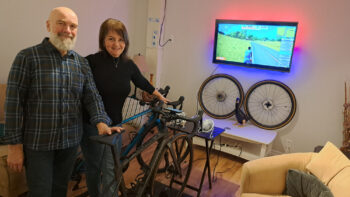 Un couple se tient devant leur vélo de route à l'intérieur de leur maison.