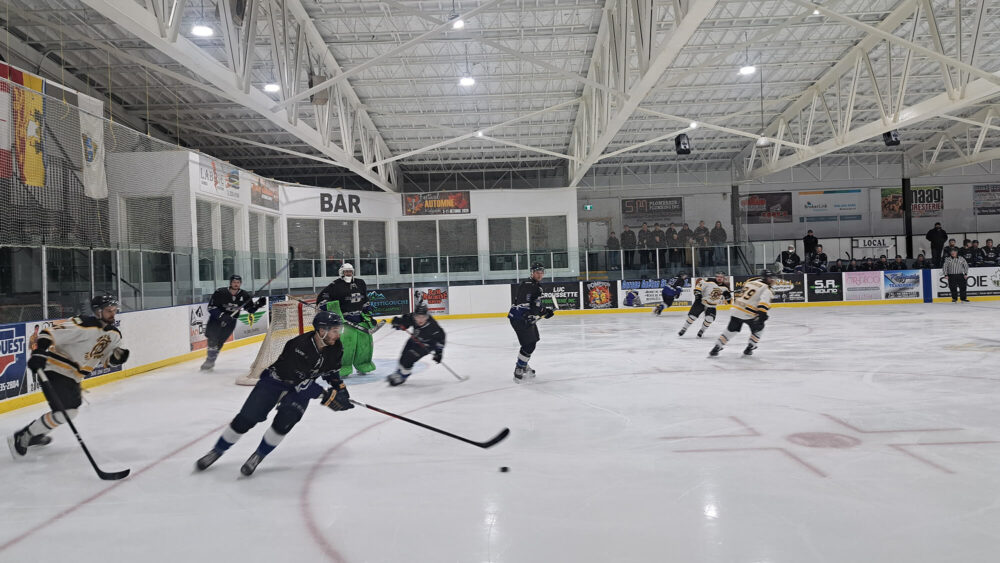 Joueurs de hockey en action sur une patinoire intérieure.