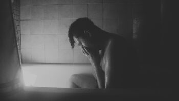 Un homme pleure dans un bain. La photo est en noir et blanc.