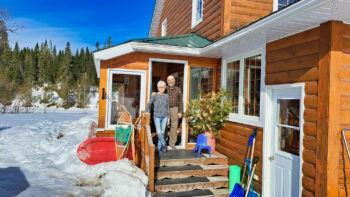 Couple au seuil de leur porte d'entrée de maison, ne portant pas de manteaux en plein hiver lors qu'une journée ensoleillée.