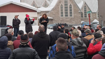 Trois personnes debout dans la boîte d'un camion s'adressent à une foule lors d'un rassemblement pacifique devant le bureau municipal de Saint-Quentin.