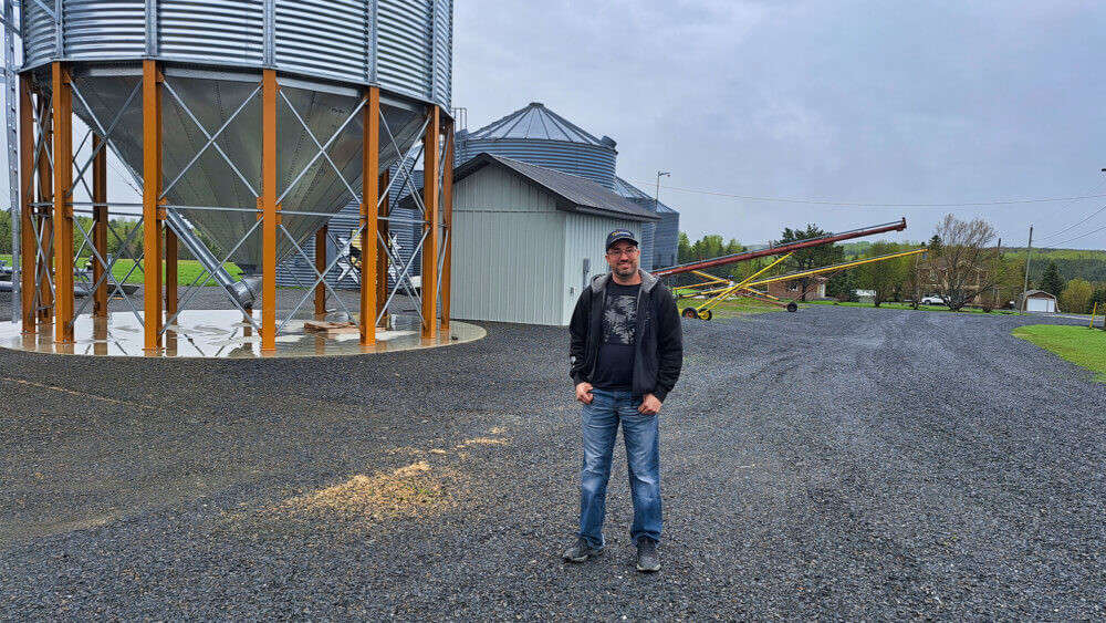 Un homme se tenant devant un silo à grains lors d'une journée pluvieuse.