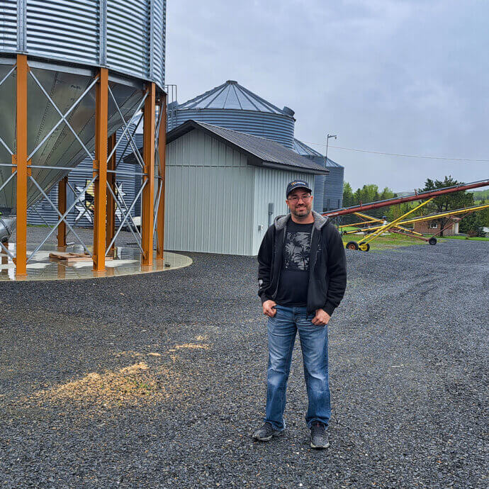 Un homme se tenant devant un silo à grains lors d'une journée pluvieuse.
