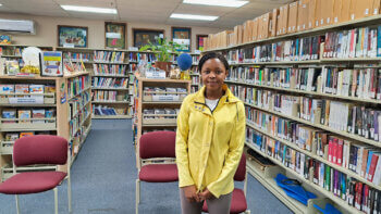 Camile Kuate vêtue d'un manteau jaune à l'intérieur de la Bibliothèque publique de Kedgwick.