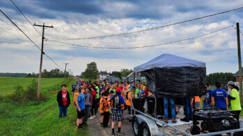 Groupe de marcheurs sur la route 260 à Saint-Quentin lors d'une journée pluvieuse.