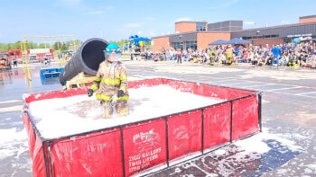 Pompier dans une piscine d'eau et de mousse lors d'un tournoi de pompier lors d'une journée ensoleillée.