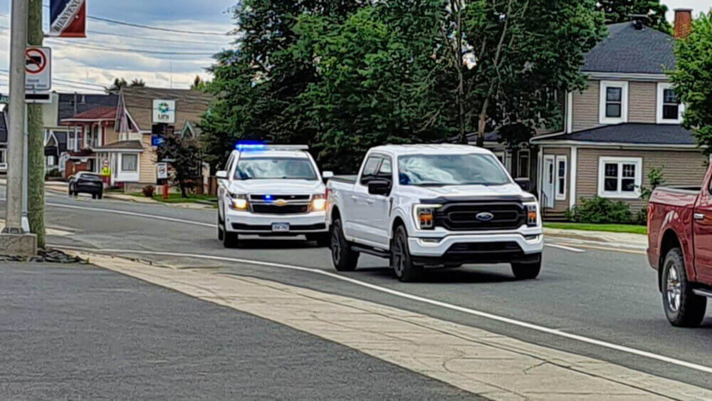 Sur la rue Canada à Saint-Quentin. Un véhicule blanc de la GRC a ses gyrophares allumés derrière une camionnette blanche.