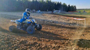 Un pilote de VTT en plein de course sur une piste de motocross lors d'une journée ensoleillée.