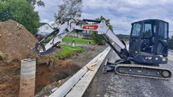 Une excavatrice blanche et noire dans un chantier de travaux routier lors d'une journée nuageuse.