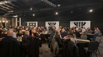 Plusieurs personnes assises autour de plusieurs tables en rond portant leur regard vers la scène lors d'un Gala