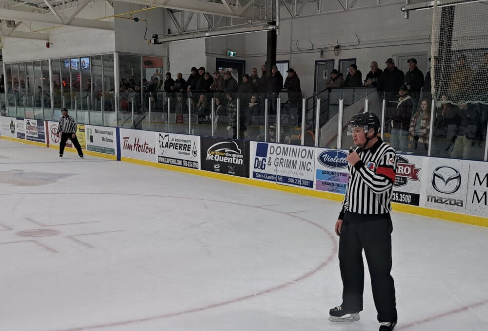 Arbitre en chef de hockey en action sur une patinoire intérieur devant les partisans présent dans les estrades