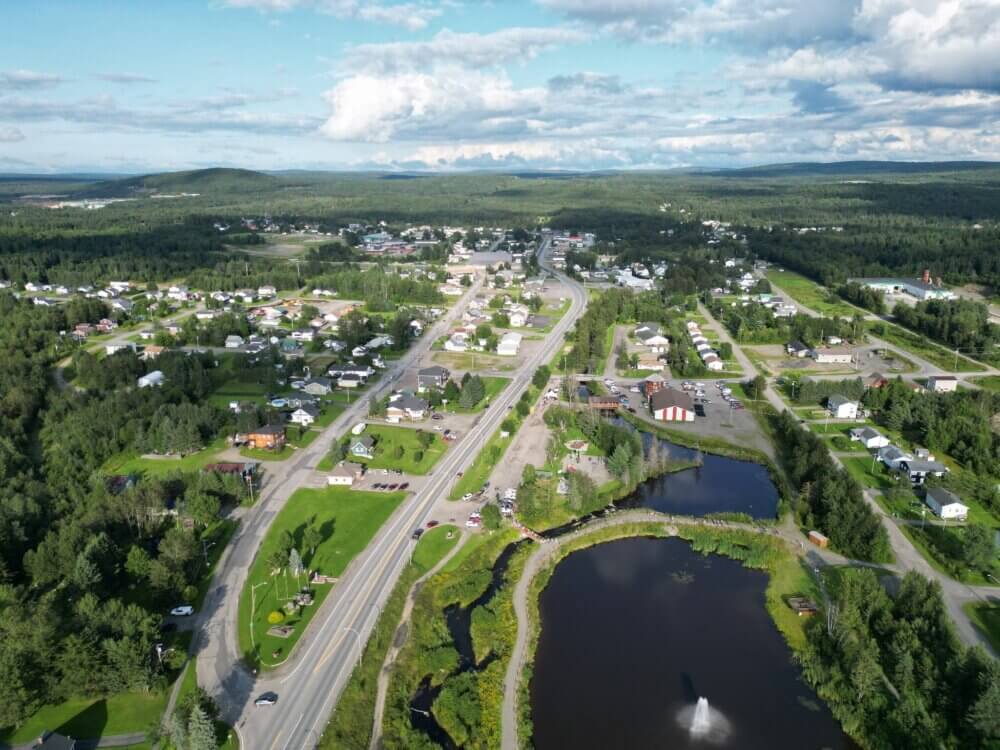 Vue aérienne de la communauté rurale de Kedgwick. Ciel nuageux et petit village entourée d'arbres et de nature.