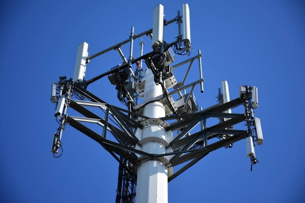 Vue sur le haut d'une tour de projection d'ondes cellulaires. Le ciel est complètement dégagé.